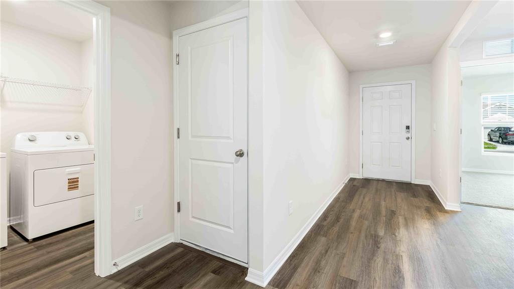 A laundry room with a white washer and dryer sits beside a hallway with wood-look flooring — 11908 MOUNTAIN ISLAND TRAIL, PARRISH, FL