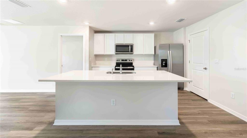 A modern kitchen features white cabinetry, stainless steel appliances, and a large central island — 11908 MOUNTAIN ISLAND TRAIL, PARRISH, FL