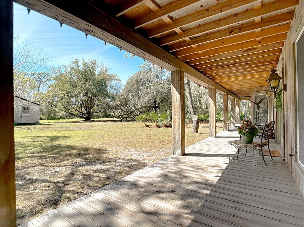 A wooden porch overlooks a grassy yard with large trees and a small shed — 3939 LAKE ERIE ROAD, GROVELAND, FL