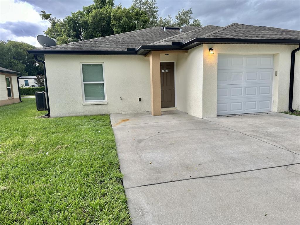 A single-story house features a tan stucco exterior, a brown front door, and a garage — 1013 KING STREET UNIT 1013, KISSIMMEE, FL