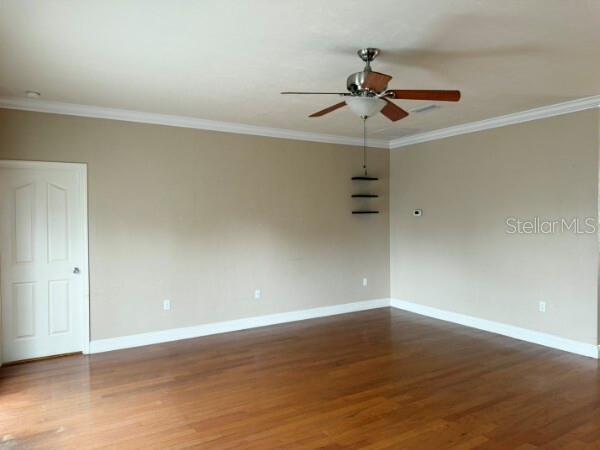 An empty room features hardwood floors, beige walls, crown molding, and a ceiling fan — 8992 SW 79TH AVENUE, GAINESVILLE, FL