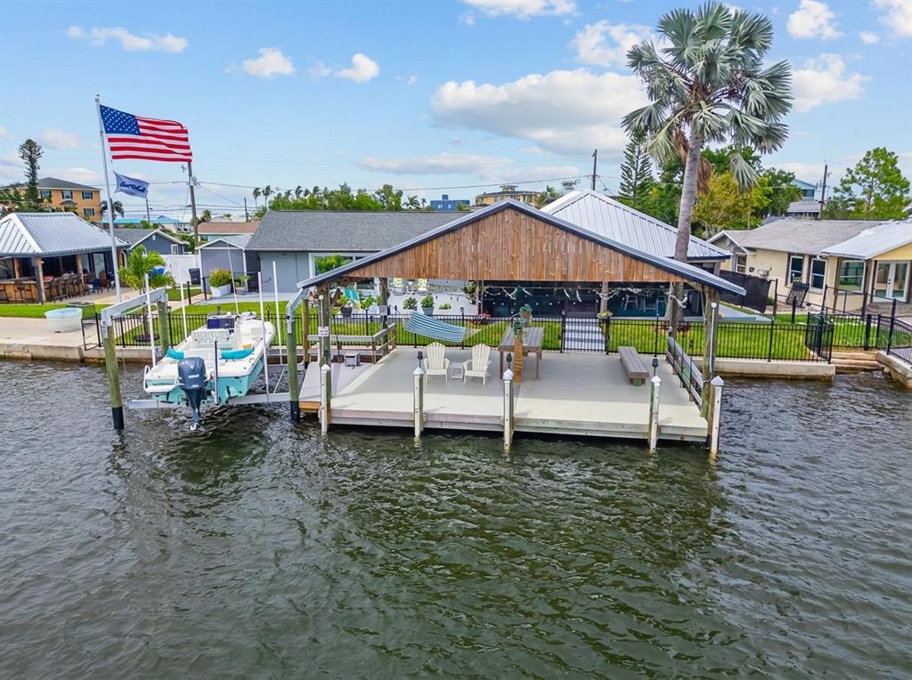 An aerial view of a waterfront dock with a covered patio, boat lift, and seating — 3422 W SHELL POINT ROAD, RUSKIN, FL