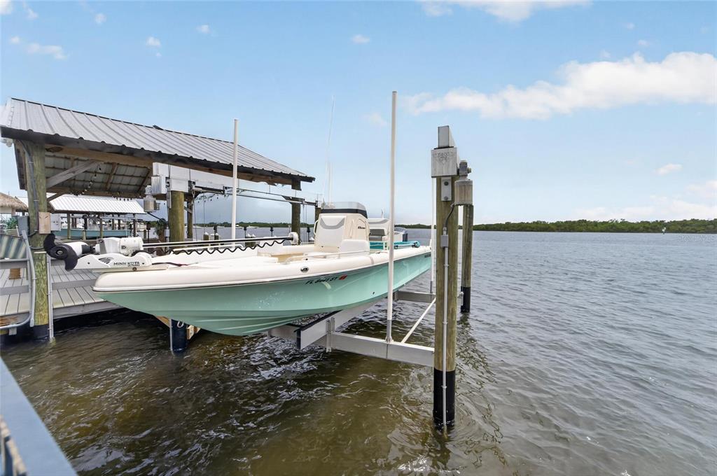 A light green motorboat sits on a mechanical lift at a wooden dock — 3422 W SHELL POINT ROAD, RUSKIN, FL