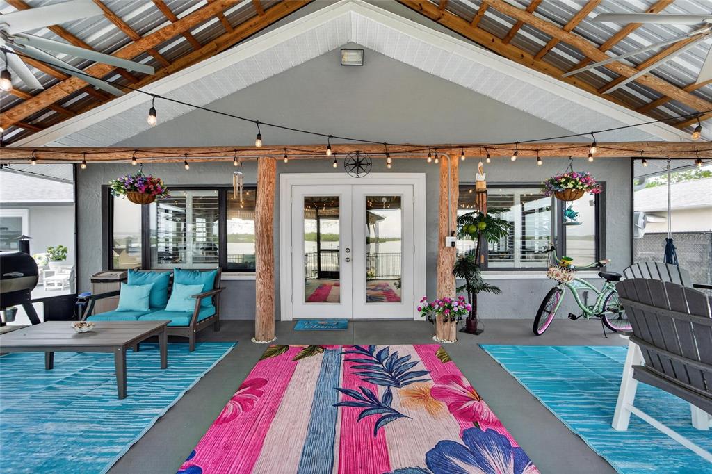A covered outdoor patio features a floral rug, seating, a bicycle, and string lights — 3422 W SHELL POINT ROAD, RUSKIN, FL