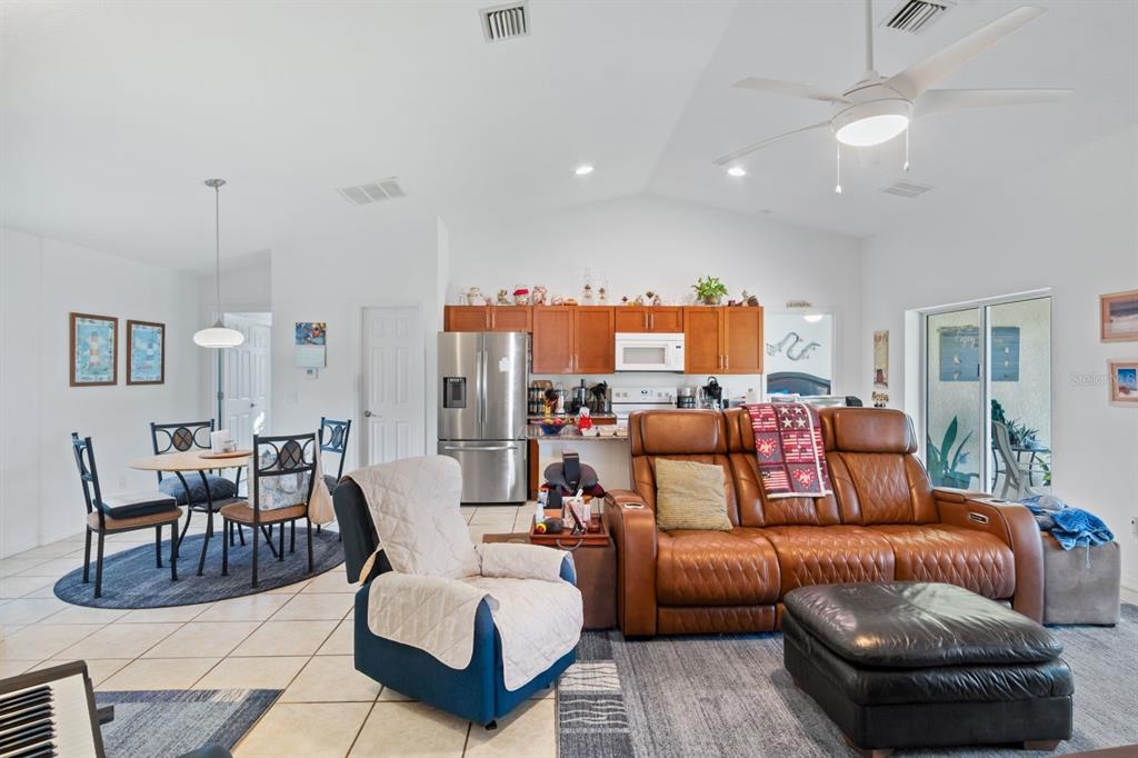 An open-concept living room and kitchen feature tile floors, a brown leather sofa, and dining area — 8232 WAWANA ROAD, NORTH PORT, FL