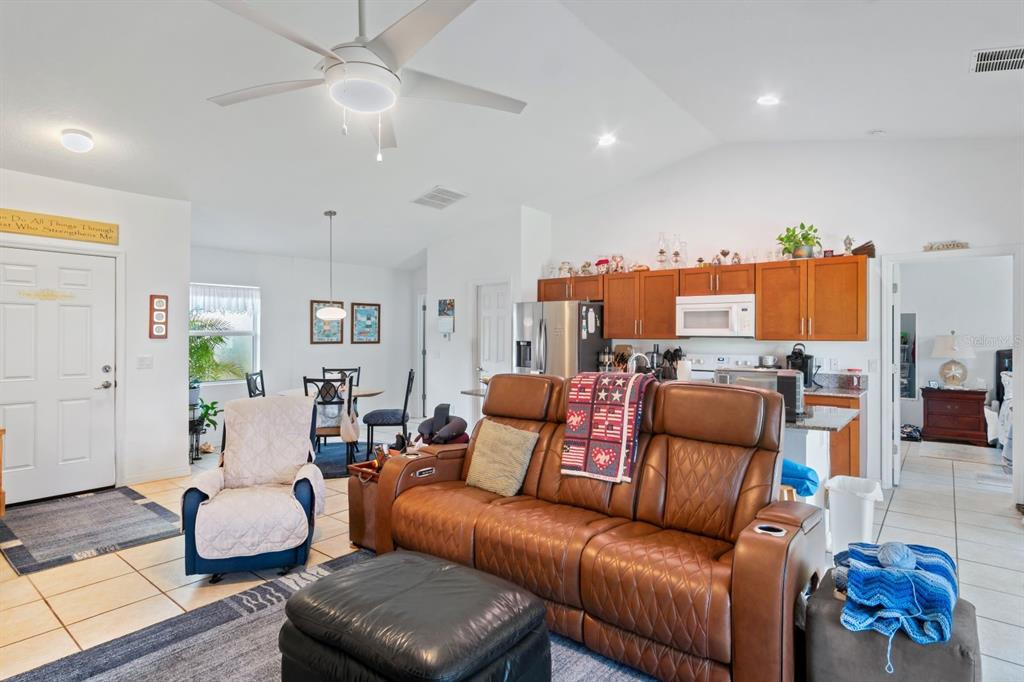 A living room with a brown leather sofa, an armchair, and an open-concept kitchen — 8232 WAWANA ROAD, NORTH PORT, FL