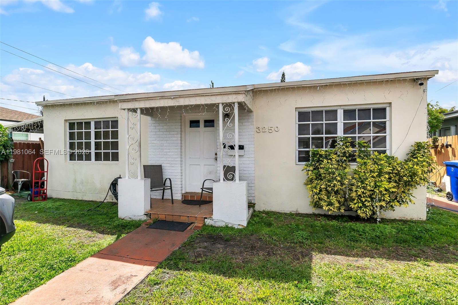 A single-story house with a white stucco facade, a small front porch, and a walkway — 3250 NW 14th Ter, Miami FL 33125, MIAMI, FL
