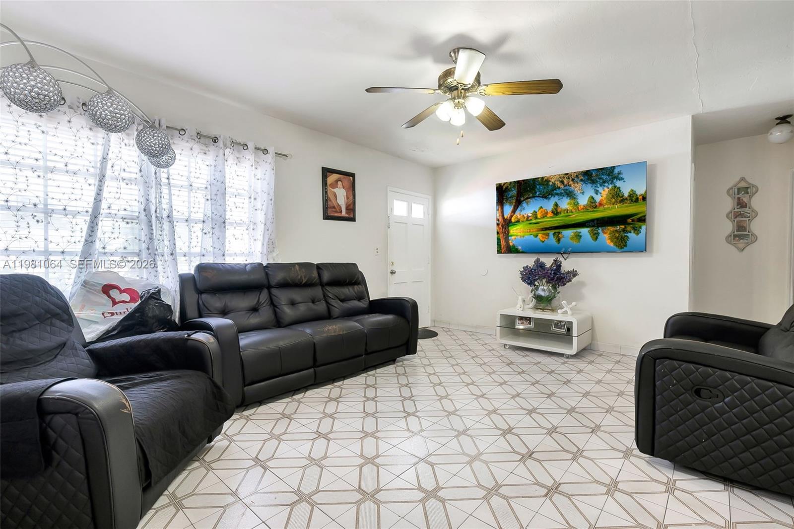 A living room features black leather furniture, patterned tile flooring, and a wall-mounted television — 3250 NW 14th Ter, Miami FL 33125, MIAMI, FL