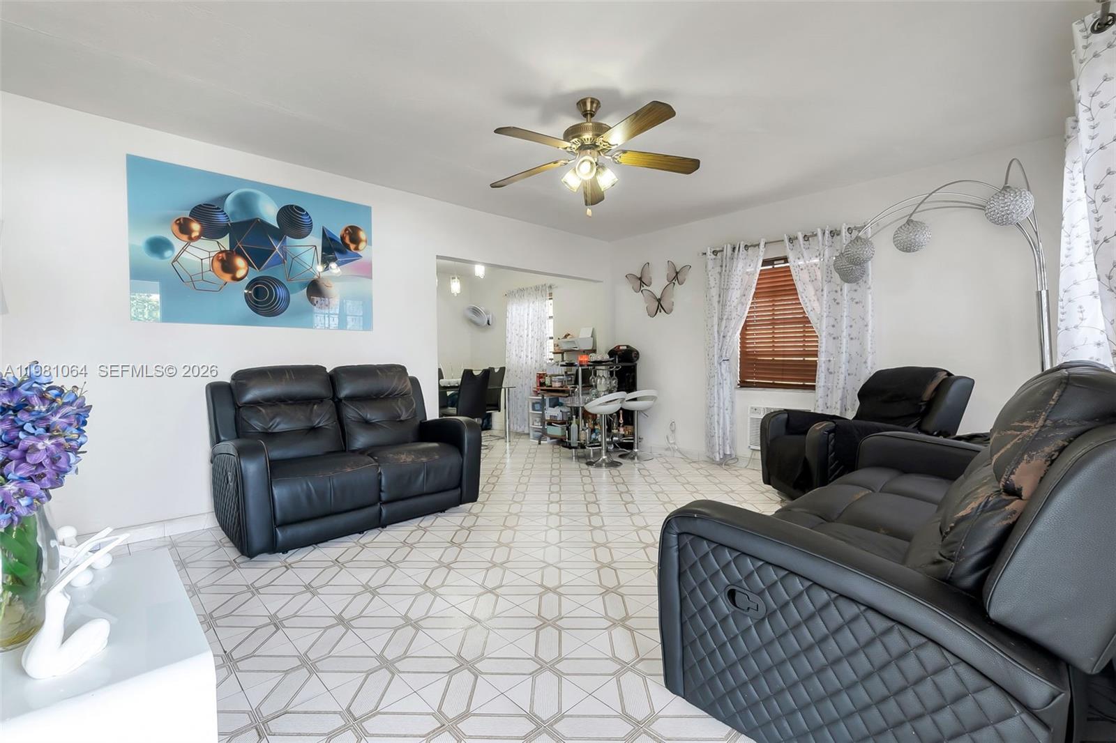 A living room features black leather furniture, a ceiling fan, and patterned tile flooring — 3250 NW 14th Ter, Miami FL 33125, MIAMI, FL