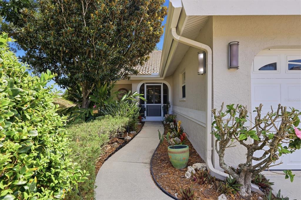 A concrete walkway leads to the front entrance of a house with a garage — 4461 ASCOT CIRCLE N, SARASOTA, FL