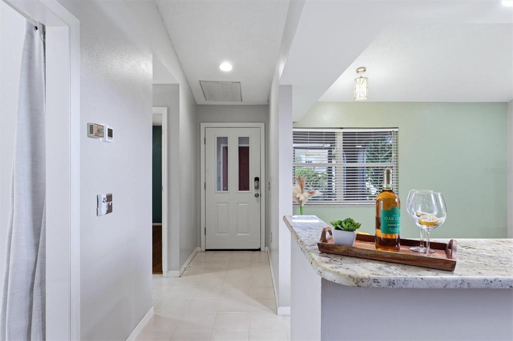 A view from a kitchen counter looking toward a white front door and hallway — 4461 ASCOT CIRCLE N, SARASOTA, FL