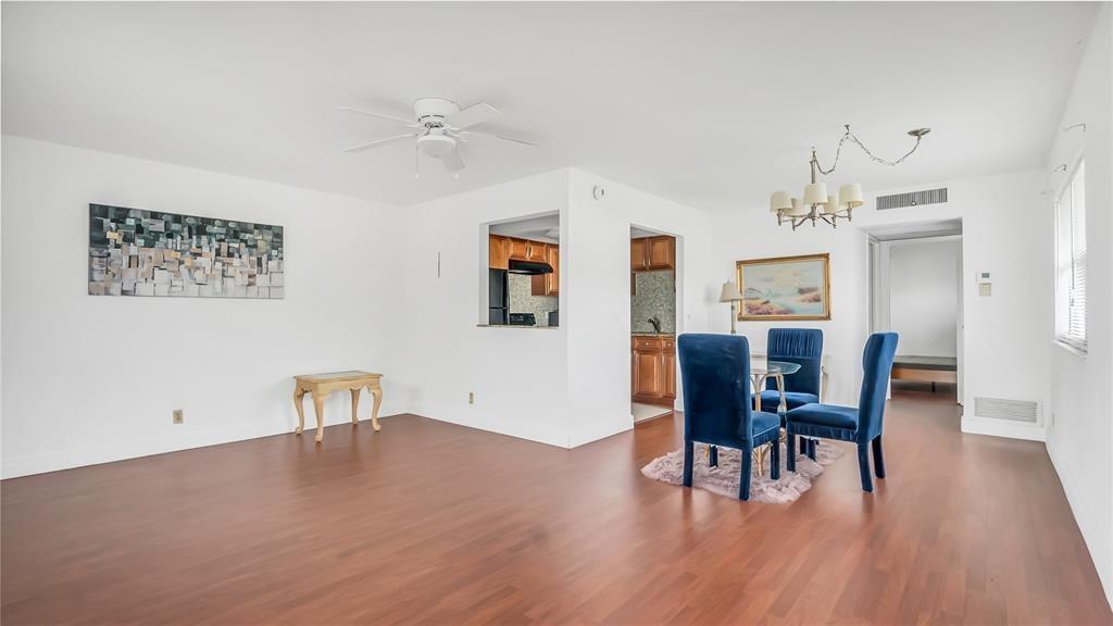 A dining area with blue velvet chairs, wood flooring, and a view into the kitchen — 703 Brittany # O, Delray Beach FL 33446, DELRAY BEACH, FL