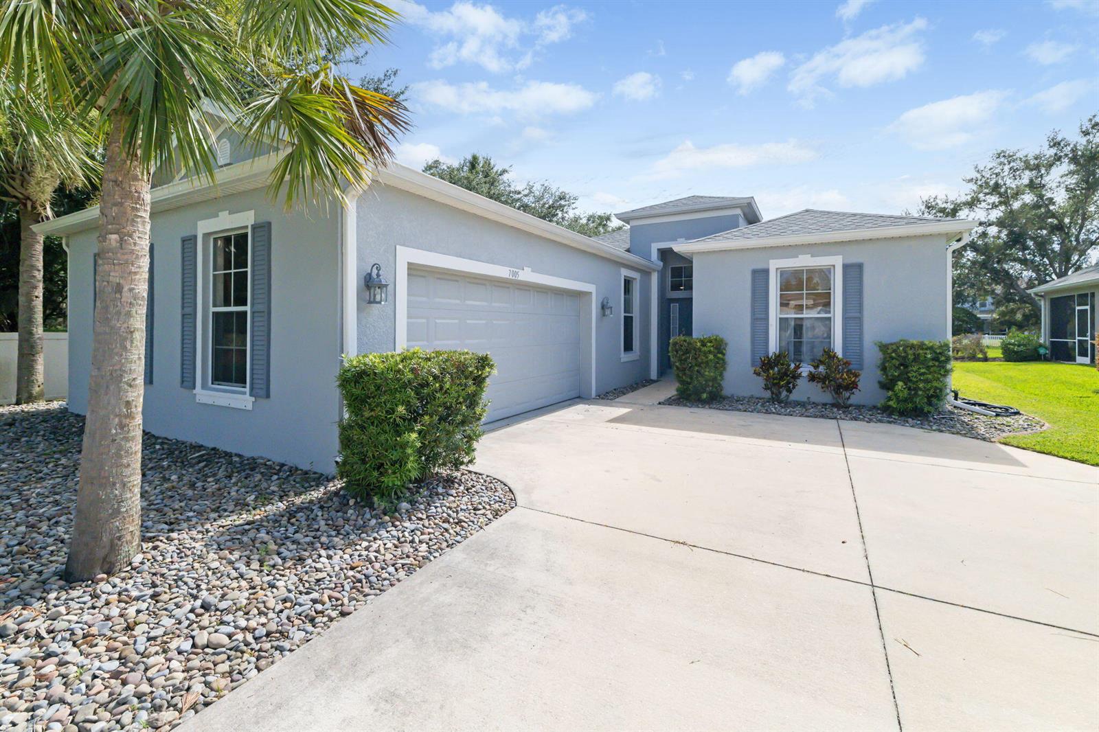A light blue single-story house features a two-car garage, a concrete driveway, and landscaping — 7005 56th Terrace E, FL 34221, FL