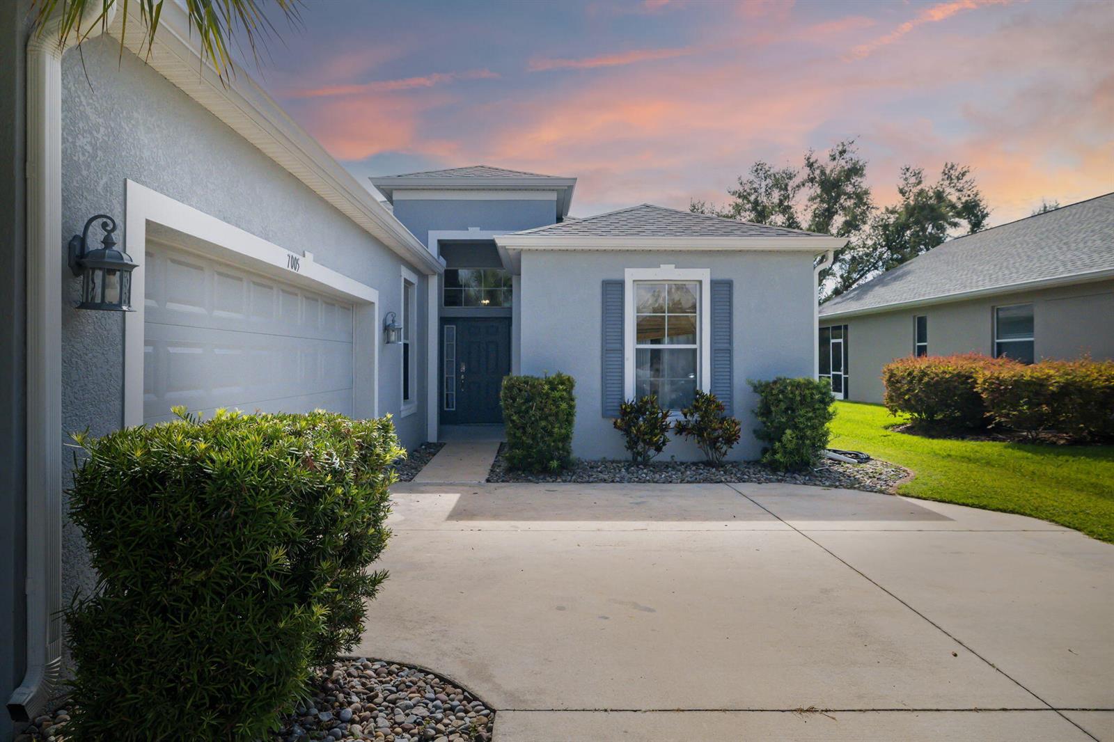 A single-story house with a blue stucco exterior, a concrete driveway, and a front entrance — 7005 56th Terrace E, FL 34221, FL