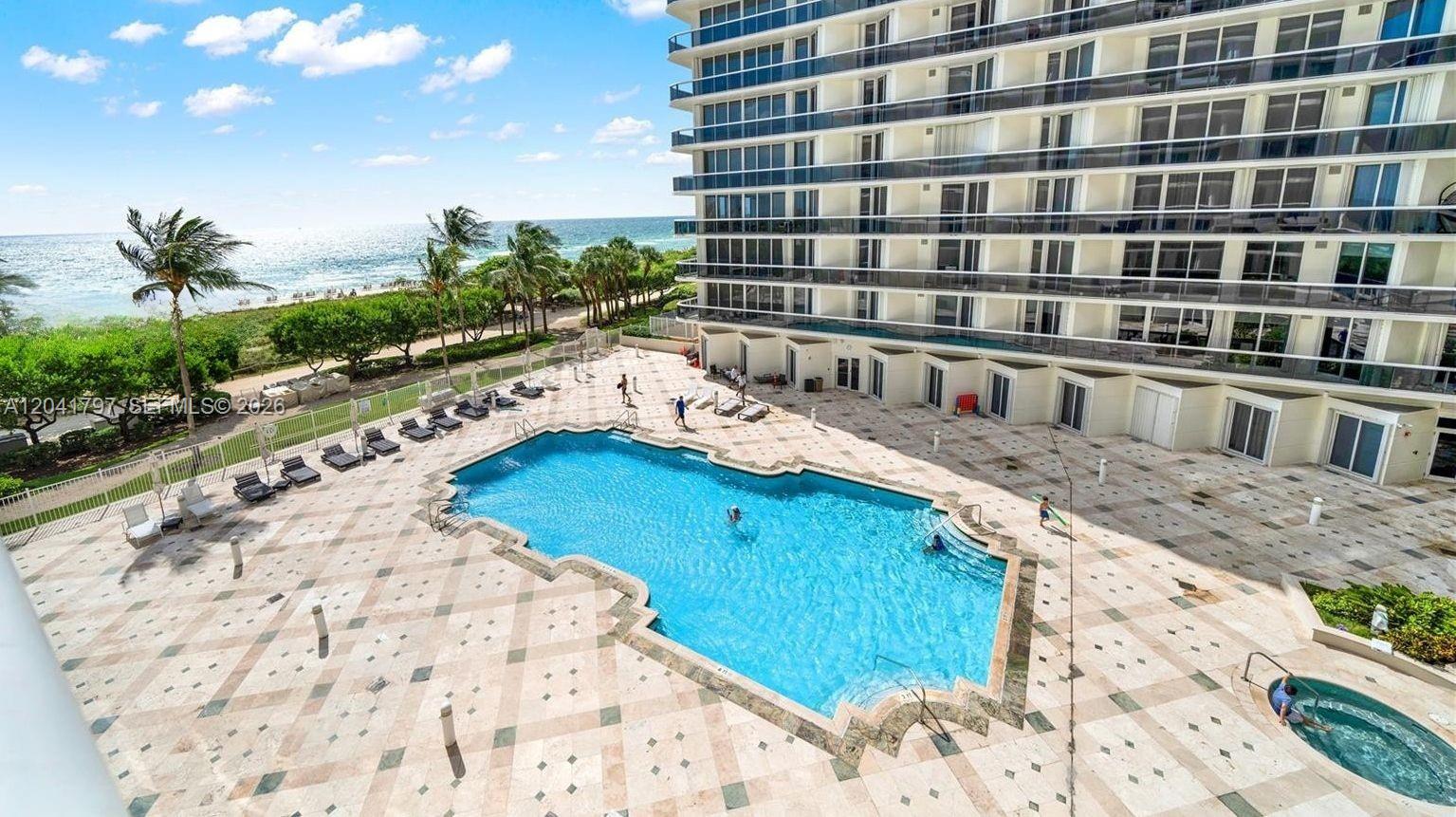 An elevated view of a swimming pool and hot tub on a paved patio deck — 9595 Collins Ave # C, Surfside FL 33154, SURFSIDE, FL