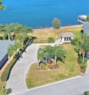 An aerial view shows a paved driveway leading to a small house near a lake — 714 MEANDERING WAY, POLK CITY, FL