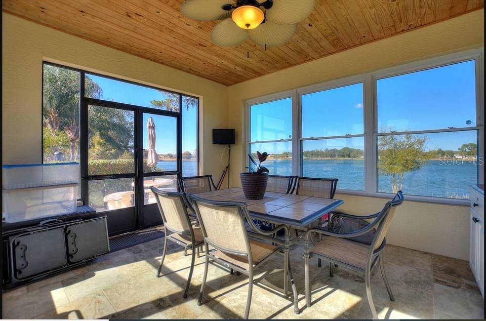 A sunroom with a tiled floor, wood-paneled ceiling, and large windows overlooking a lake — 714 MEANDERING WAY, POLK CITY, FL