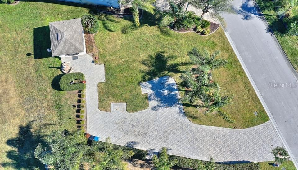 An aerial view shows a paved driveway leading to a small detached building and landscaping — 714 MEANDERING WAY, POLK CITY, FL