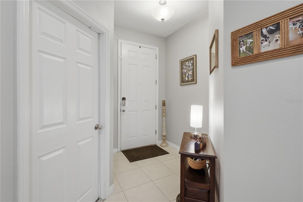 An entryway features a white front door, tile flooring, a console table, and wall decor — 4844 CLIVEDEN LOOP, SANFORD, FL