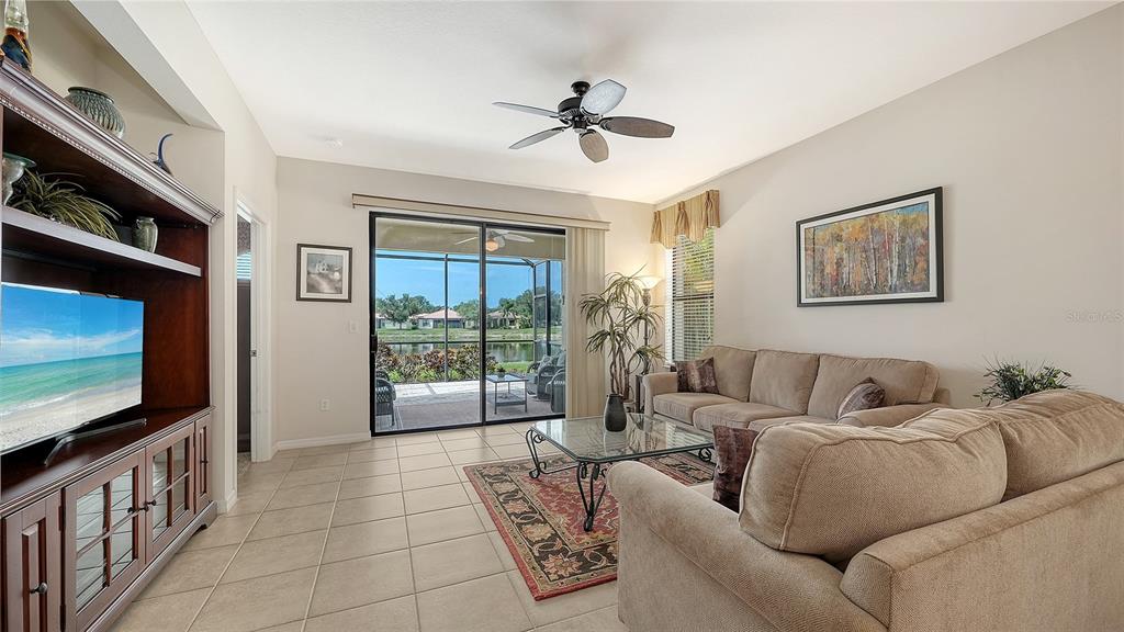 A living room features a beige sofa, a glass coffee table, and sliding glass doors — 11109 CAMPAZZO DRIVE, VENICE, FL