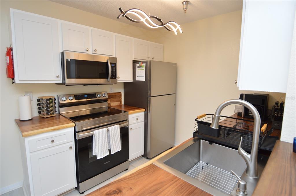 A kitchen features white cabinets, stainless steel appliances, and wood countertops — 10263 GANDY BOULEVARD N UNIT 414, ST PETERSBURG, FL