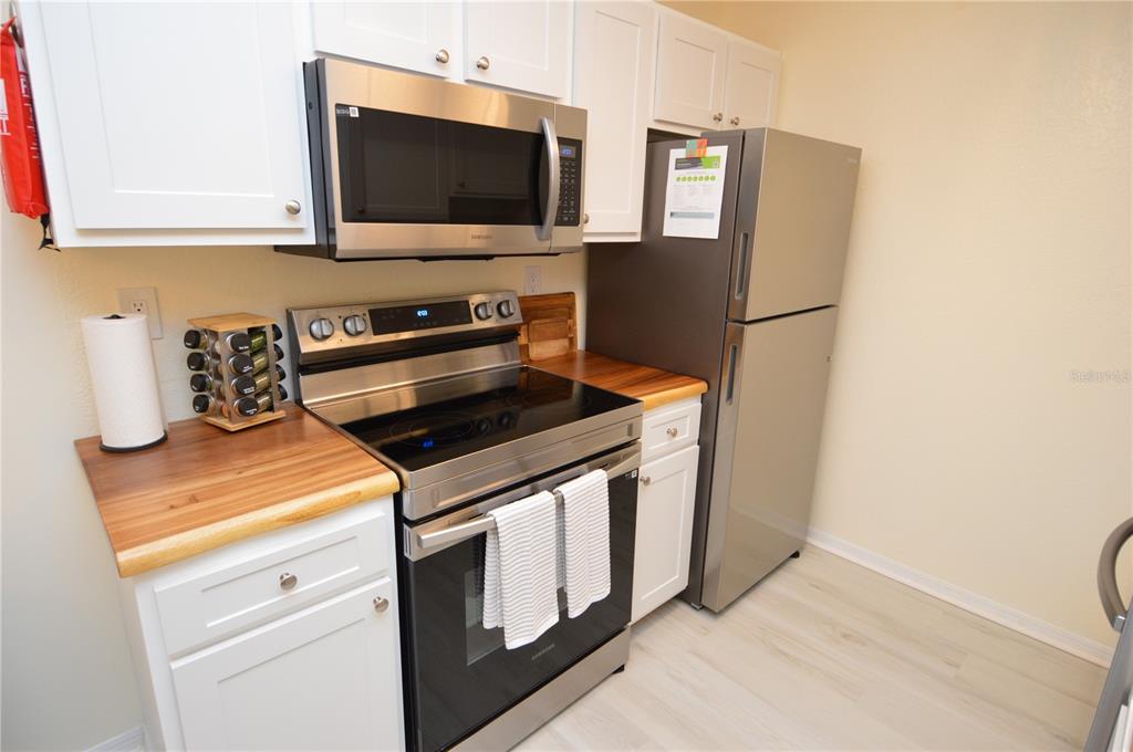 A kitchen features white cabinets, stainless steel appliances, and a wood countertop — 10263 GANDY BOULEVARD N UNIT 414, ST PETERSBURG, FL