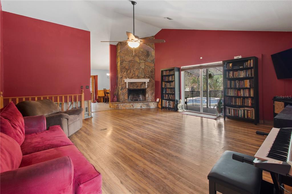 A living room features red walls, a stone fireplace, wood flooring, and a sliding glass door — 1143 MEYERS ROAD, VENICE, FL
