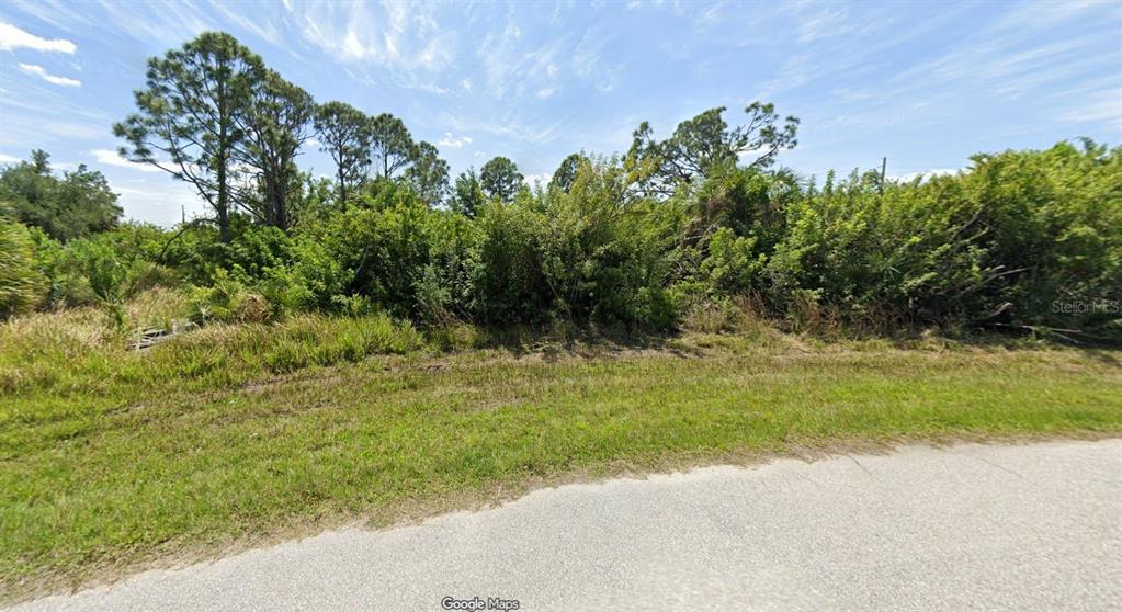 A vacant, overgrown lot with trees and shrubs sits next to a paved road — 10475 KIDRON AVENUE, ENGLEWOOD, FL