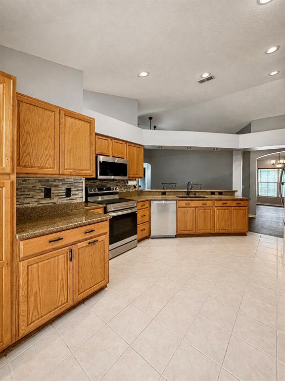 A kitchen features oak cabinets, granite countertops, stainless steel appliances, and light-colored tile flooring — 4828 WESSEX WAY, LAND O LAKES, FL