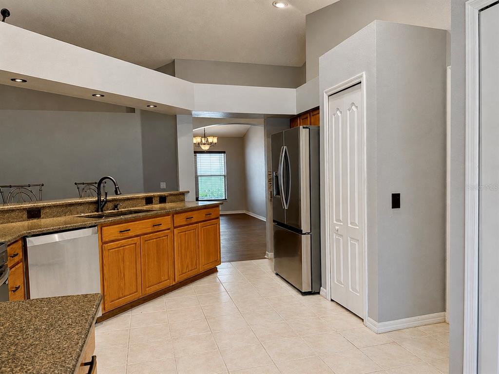 A kitchen features wood cabinets, granite countertops, stainless steel appliances, and tile flooring — 4828 WESSEX WAY, LAND O LAKES, FL