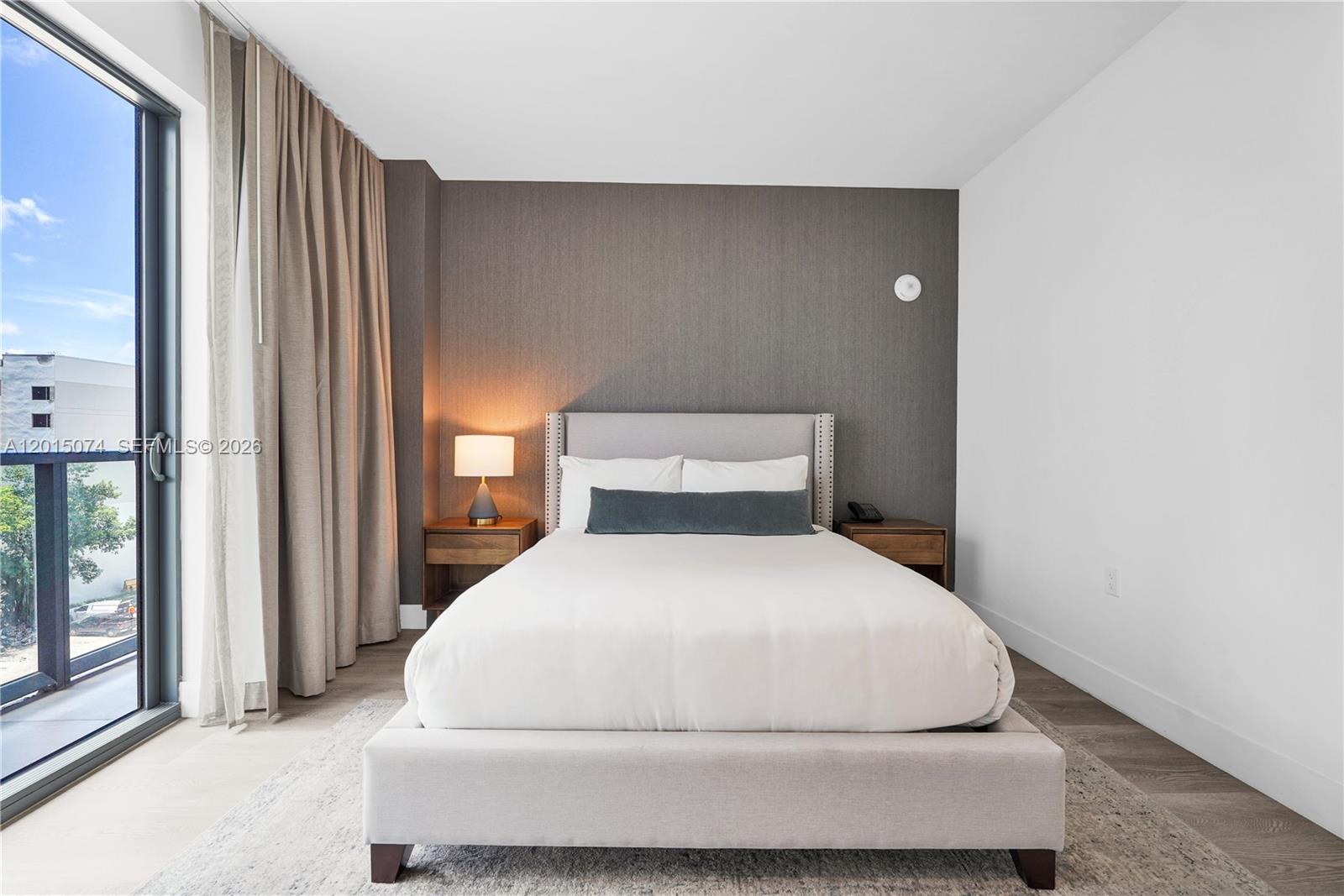 A bedroom features a bed with a gray headboard, dark accent wall, and balcony access — 229 SW 9th St # 404, Miami FL 33130, MIAMI, FL