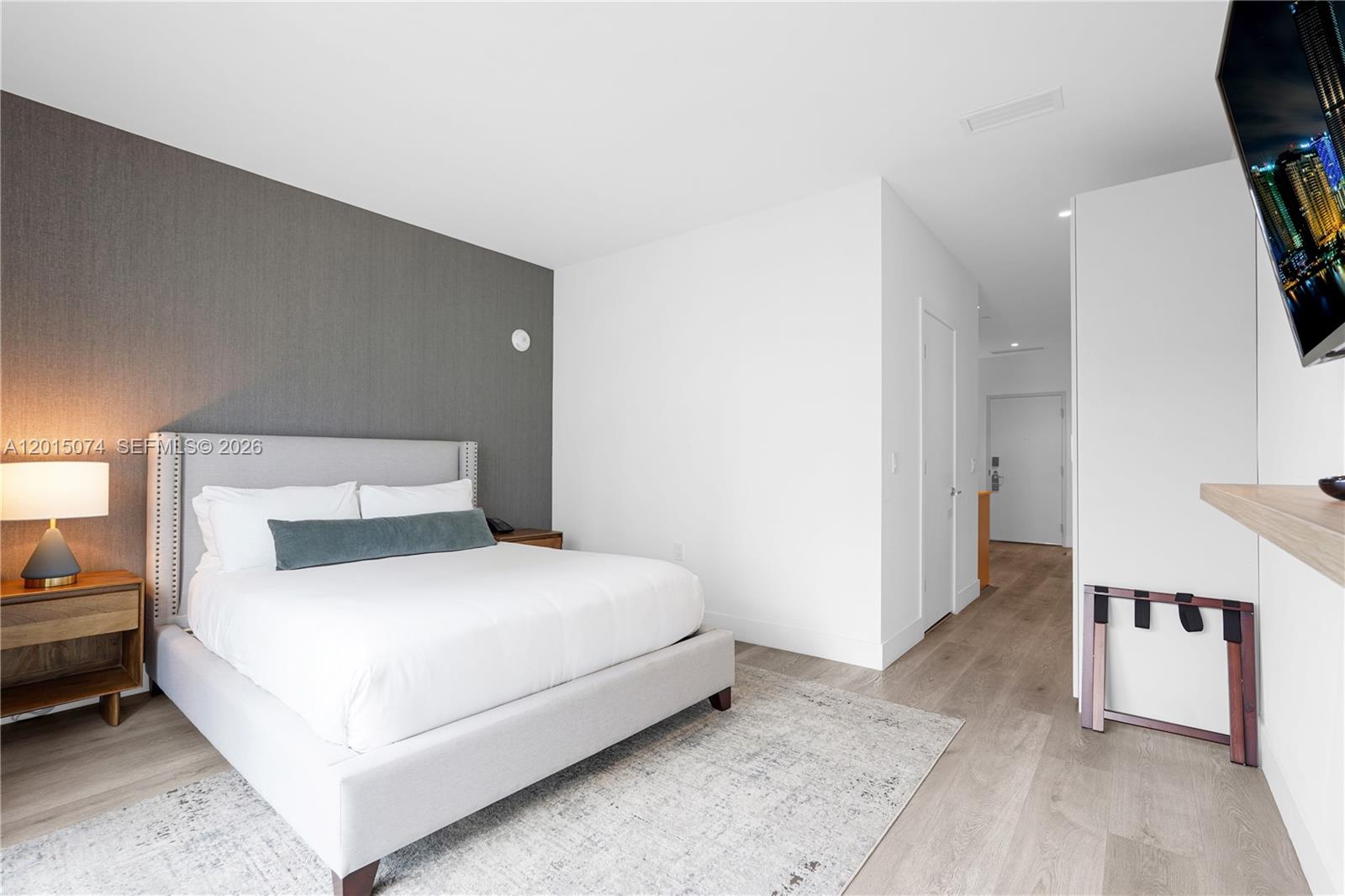 A modern bedroom features a gray upholstered bed, a dark accent wall, and wood flooring — 229 SW 9th St # 404, Miami FL 33130, MIAMI, FL