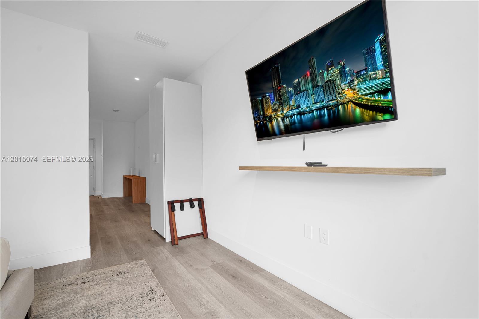 A minimalist room features a wall-mounted television, a floating shelf, and light wood flooring — 229 SW 9th St # 404, Miami FL 33130, MIAMI, FL