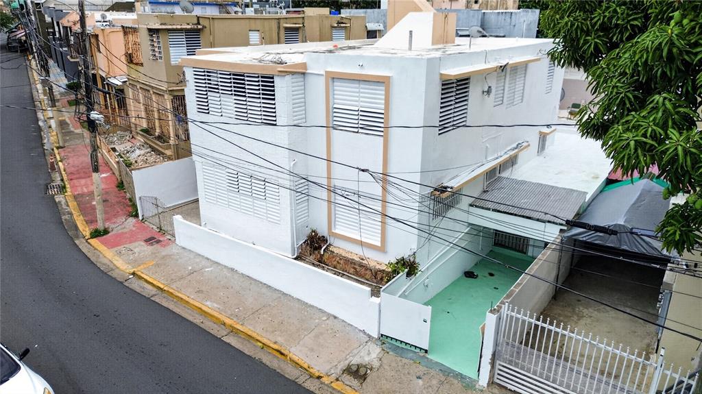 An elevated exterior view of a white two-story house with louvered windows and a carport — 162 LA PLACITA DE SANTURCE, DOS HERMANOS, SAN JUAN, PR