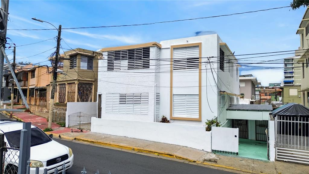 A two-story white building with louvered windows and a small carport on a street — 162 LA PLACITA DE SANTURCE, DOS HERMANOS, SAN JUAN, PR