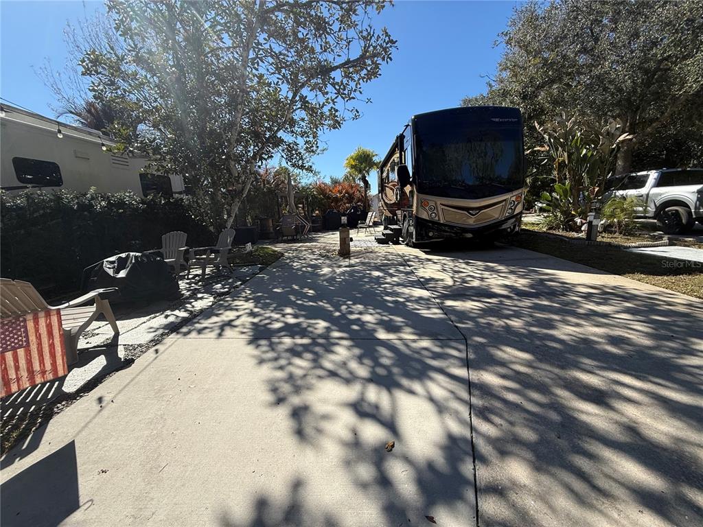 A large recreational vehicle is parked on a concrete driveway surrounded by trees — 124 STALLION LANE, LAKE WALES, FL