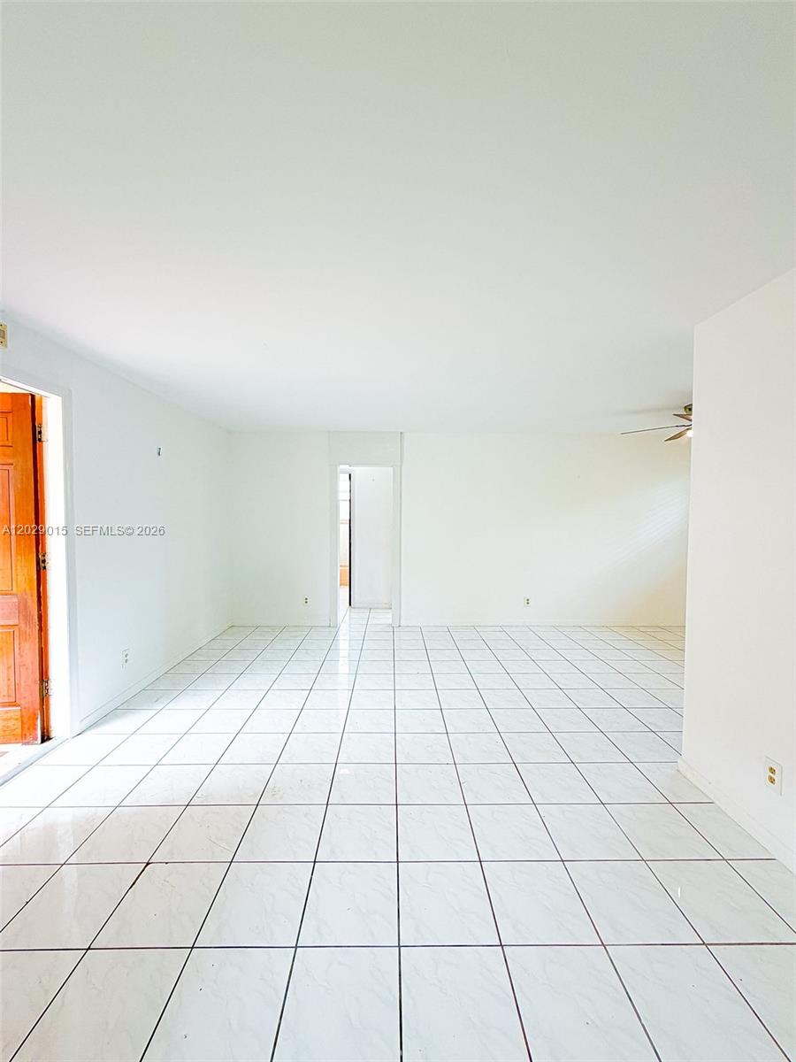 An empty room features white tiled floors, white walls, and a doorway leading to another area — 1401 Grant St # 3, Hollywood FL 33020, HOLLYWOOD, FL