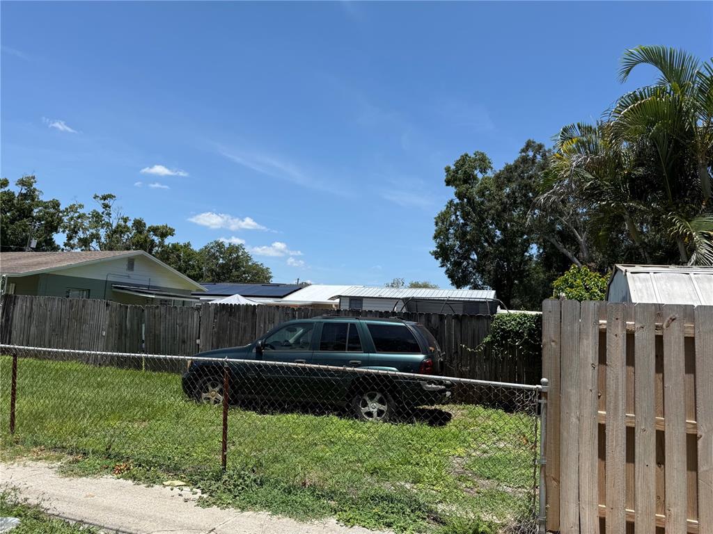 A dark green SUV is parked on a grassy lot behind a chain-link fence — 4305 W BROAD STREET, TAMPA, FL