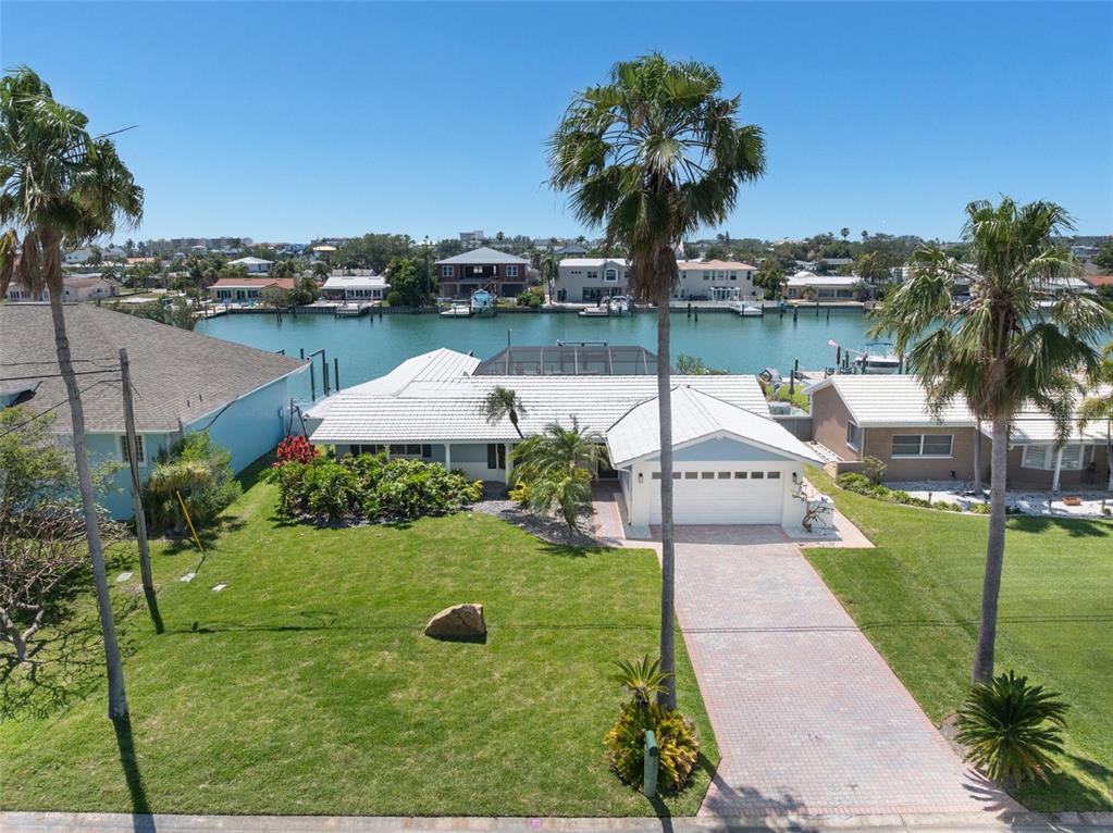 An aerial view shows a single-story house with a white roof, driveway, and palm trees — 11900 7TH STREET E, TREASURE ISLAND, FL