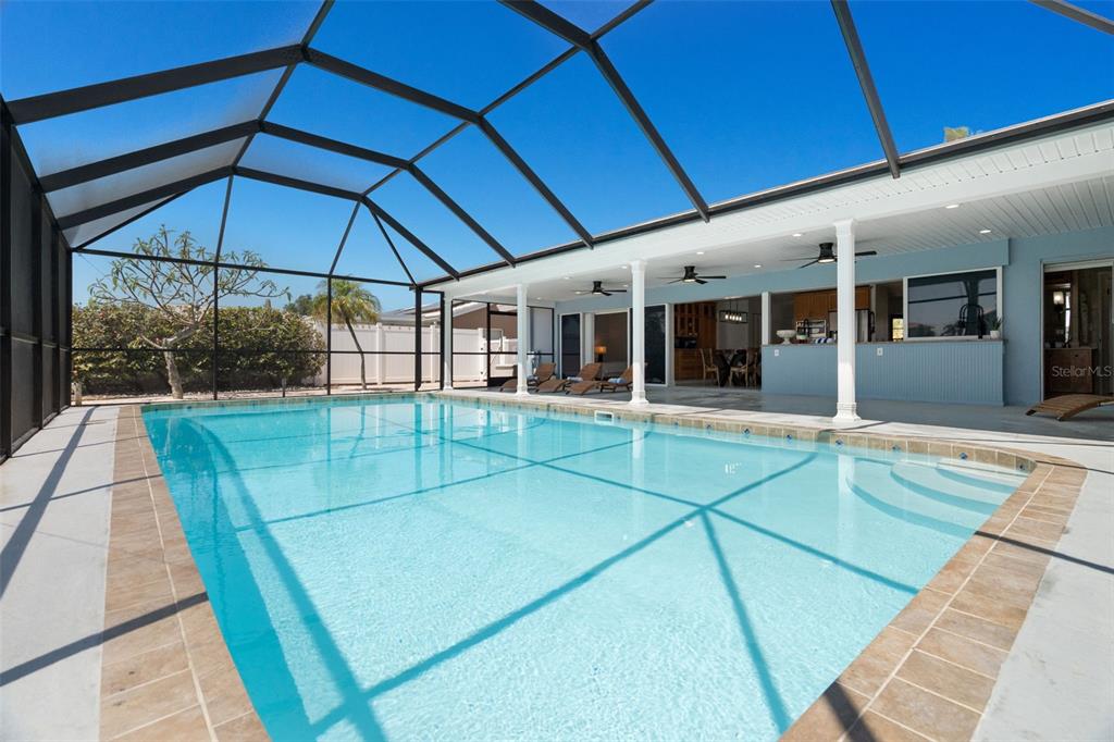 A swimming pool with a screened enclosure and a covered patio area — 11900 7TH STREET E, TREASURE ISLAND, FL