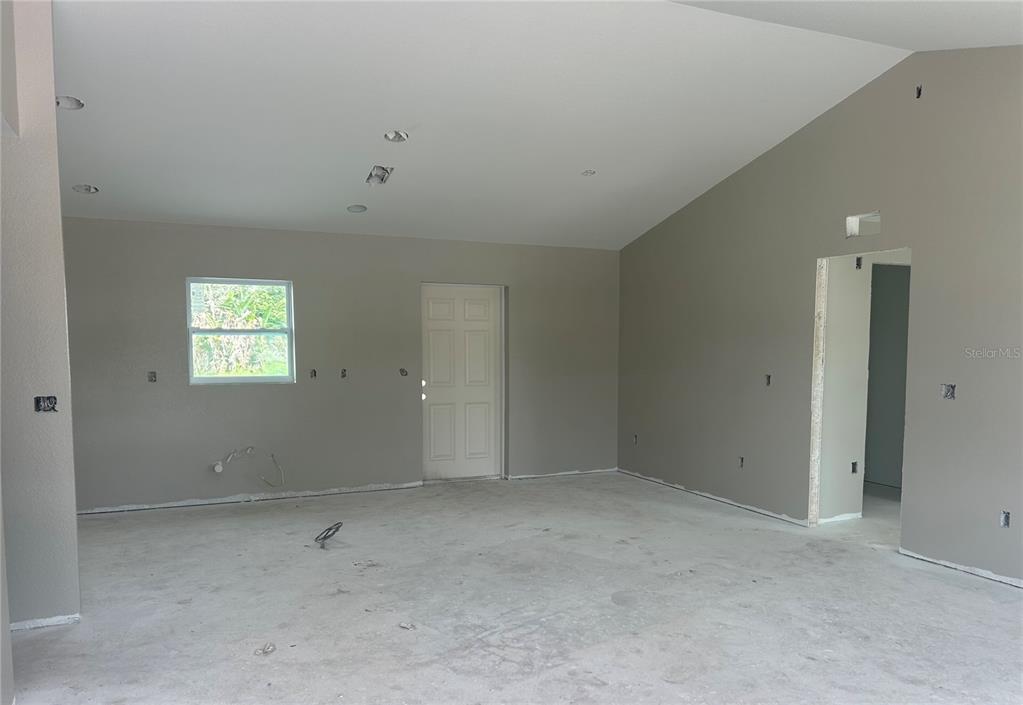 An unfinished room with gray walls, a white door, and a concrete floor — 11506 SW LEMON AVENUE, ARCADIA, FL