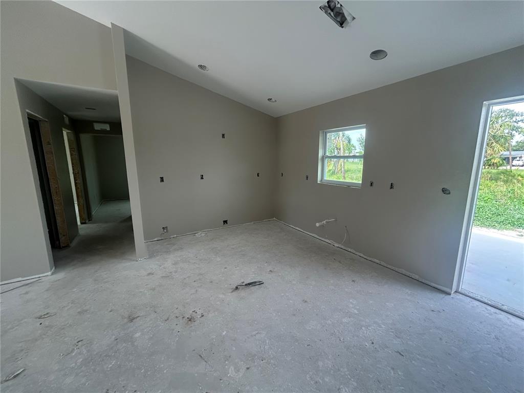 An unfinished room features gray walls, a concrete floor, a window, and a sliding door — 11506 SW LEMON AVENUE, ARCADIA, FL