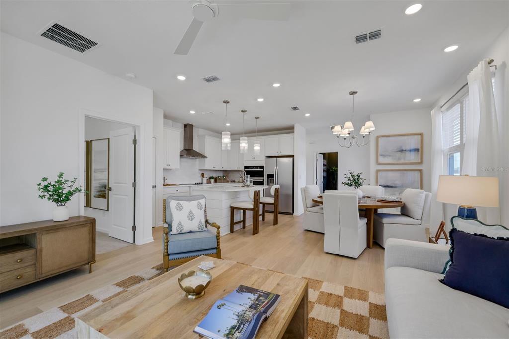 An open-concept living and dining area features white cabinetry, light wood floors, and neutral furniture — 35 BIG PINE DRIVE, PALM COAST, FL