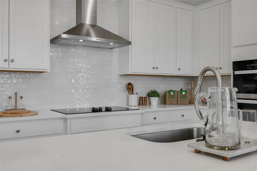 A modern kitchen features white cabinetry, a stainless steel range hood, and a white backsplash — 35 BIG PINE DRIVE, PALM COAST, FL
