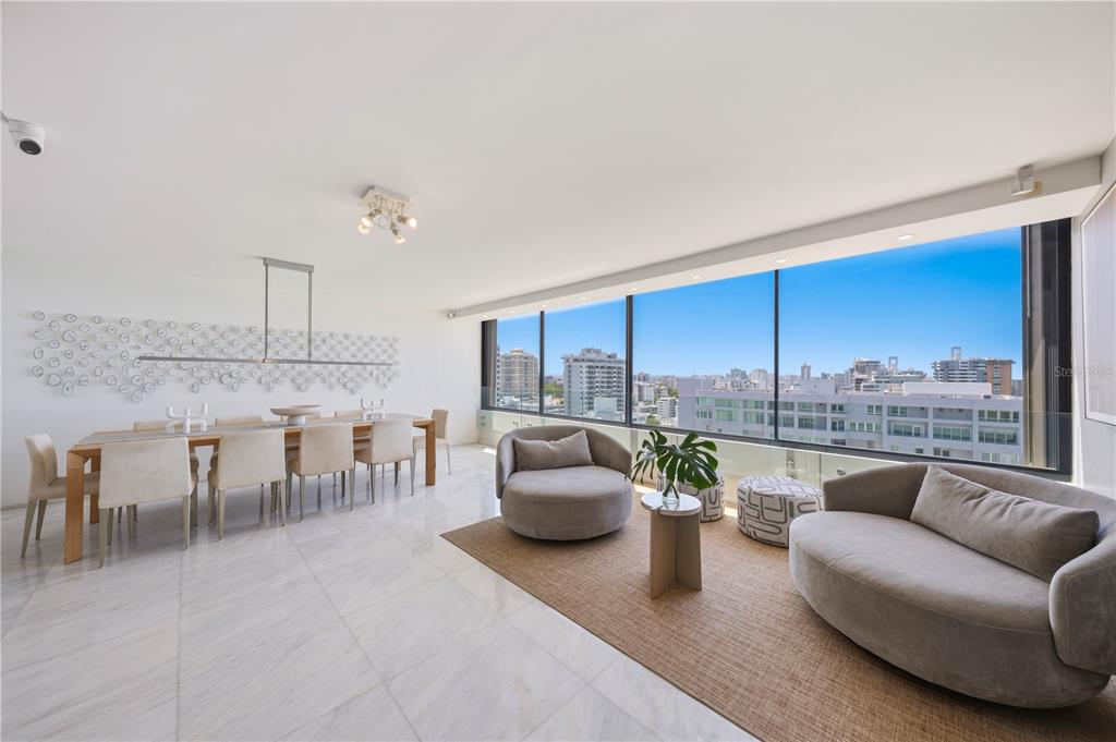 A modern dining and living area features floor-to-ceiling windows with city views and marble flooring — 1 TAFT STREET UNIT Penthouse-C, SAN JUAN, PR