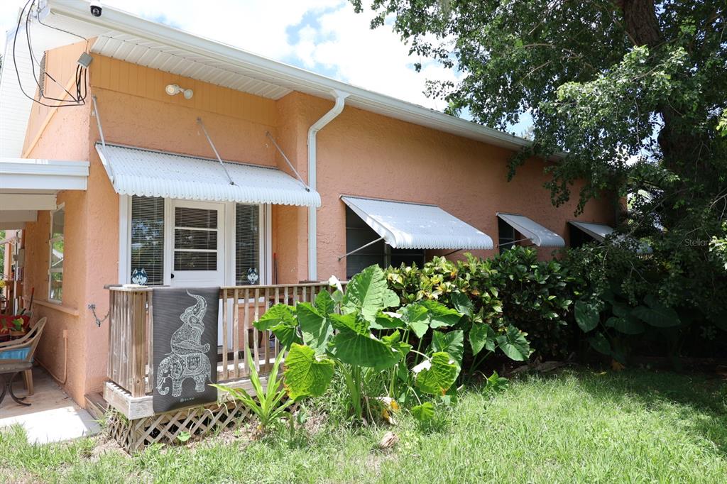 A peach-colored house exterior features a wooden deck, white metal awnings, and large green plants — 3250 TAYLOR ROAD, PUNTA GORDA, FL
