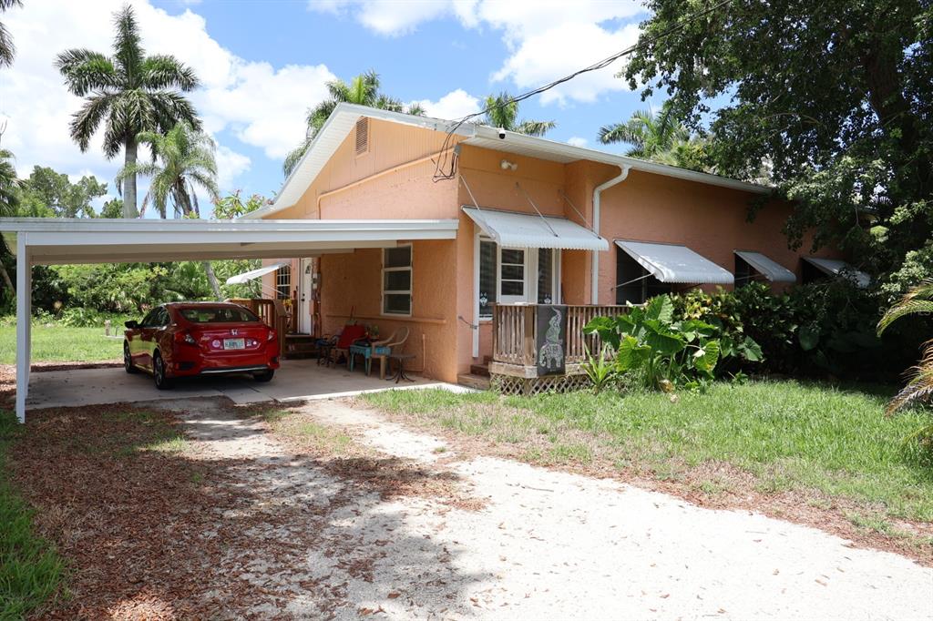 A peach-colored house with a carport, a red car, and a wooden front porch — 3250 TAYLOR ROAD, PUNTA GORDA, FL