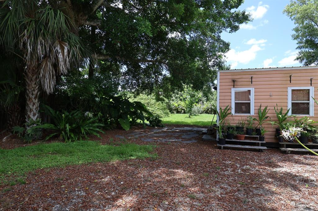 A small peach-colored structure sits beside a large tree in a yard with scattered leaves — 3250 TAYLOR ROAD, PUNTA GORDA, FL