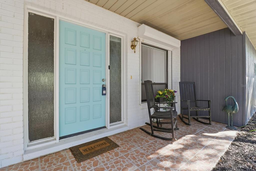 A front porch features a light blue door, two rocking chairs, and tiled flooring — 98 SYCAMORE CIRCLE, HOMOSASSA, FL