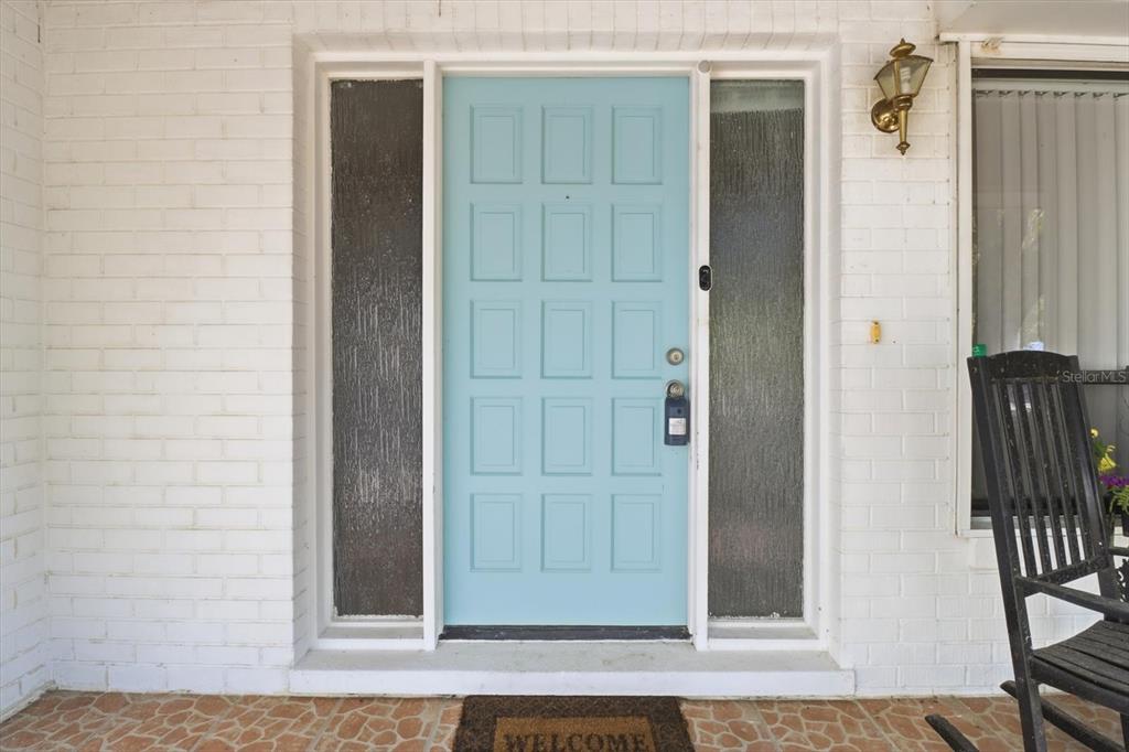 A light blue front door with side windows is set into a white brick wall — 98 SYCAMORE CIRCLE, HOMOSASSA, FL